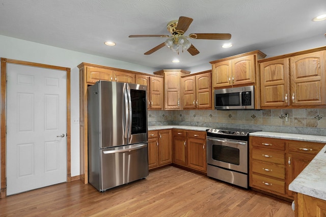 kitchen featuring light countertops, tasteful backsplash, stainless steel appliances, and light wood-type flooring