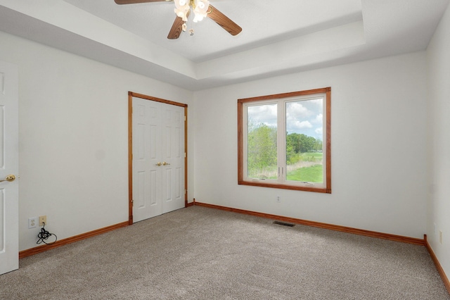 carpeted spare room with baseboards, a ceiling fan, and visible vents