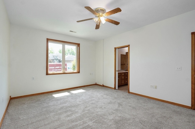 carpeted spare room with baseboards, a ceiling fan, and visible vents