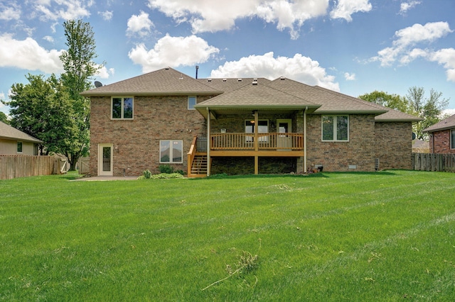 rear view of house featuring fence, brick siding, a wooden deck, stairway, and a lawn