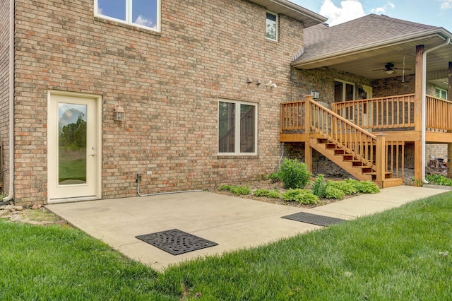 back of property with ceiling fan, a yard, stairway, and brick siding
