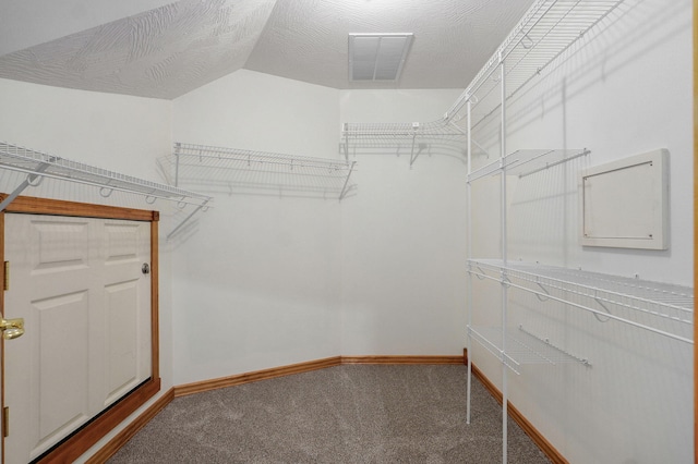 walk in closet with visible vents, carpet floors, and vaulted ceiling