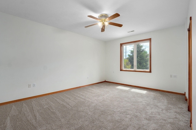 carpeted empty room with baseboards, ceiling fan, and visible vents