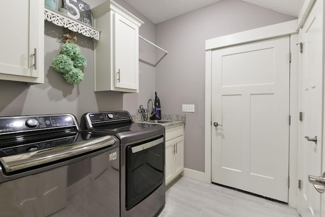 washroom with baseboards, a sink, cabinet space, and washer and dryer