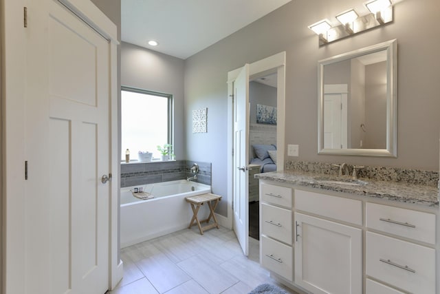 full bath featuring vanity, baseboards, and a garden tub