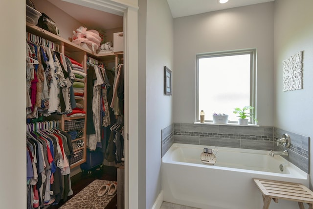 bathroom with a walk in closet and a bath