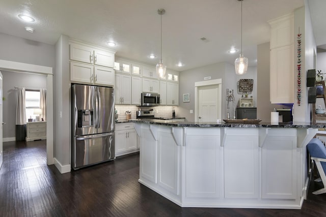 kitchen featuring dark stone counters, decorative backsplash, white cabinets, and stainless steel appliances