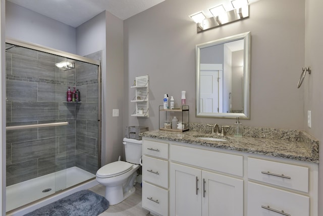 full bathroom featuring vanity, a stall shower, and toilet