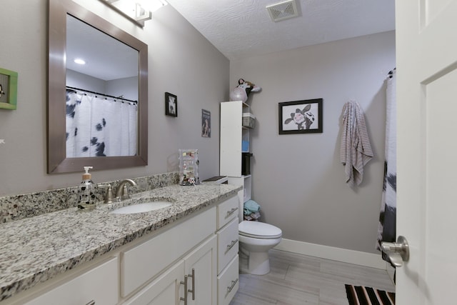 bathroom with vanity, baseboards, toilet, and visible vents