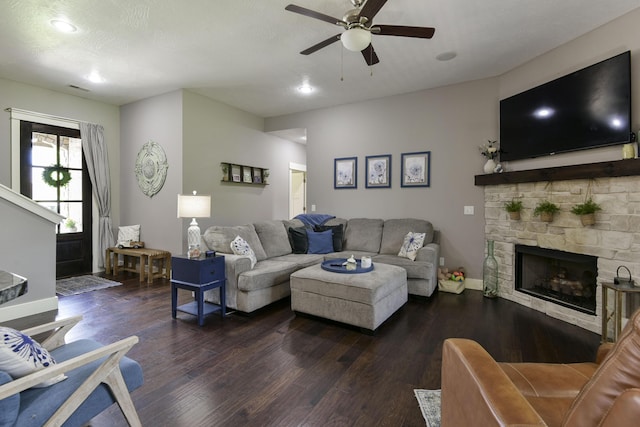 living area featuring ceiling fan, dark wood-style flooring, a stone fireplace, baseboards, and recessed lighting