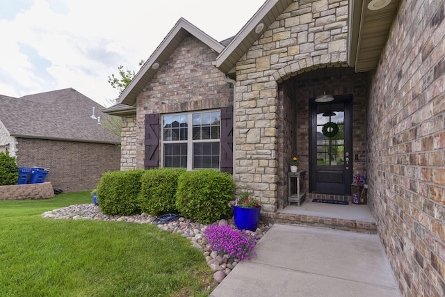 view of exterior entry featuring a yard, brick siding, and stone siding