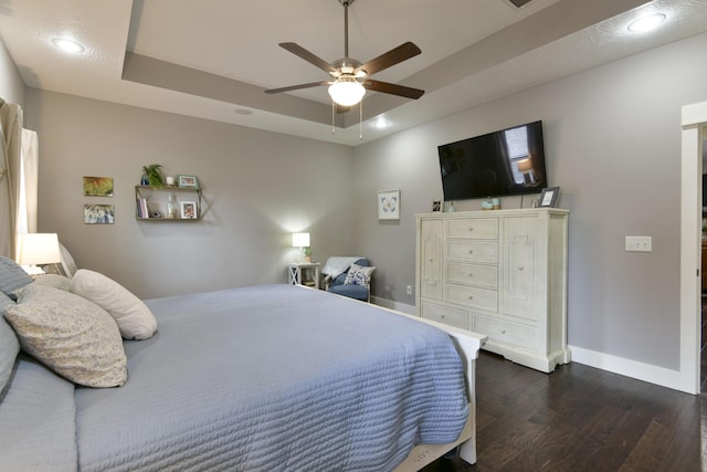 bedroom with baseboards, recessed lighting, a raised ceiling, and dark wood-style floors