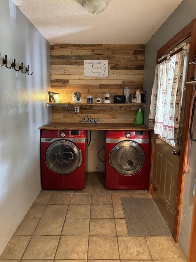 laundry room featuring laundry area, wood walls, a textured ceiling, and independent washer and dryer