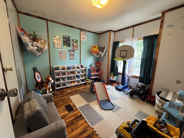 playroom featuring crown molding, a textured ceiling, and wood finished floors