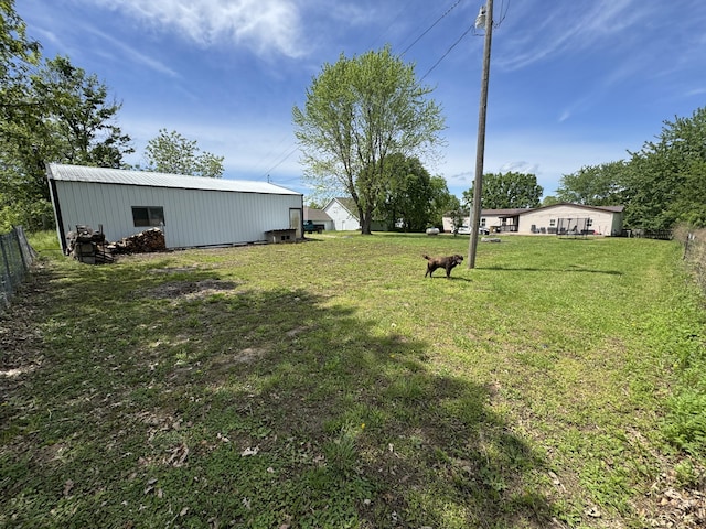 view of yard featuring fence, a pole building, and an outdoor structure