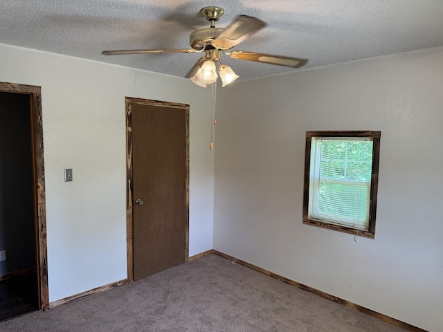 carpeted spare room featuring ceiling fan and a textured ceiling