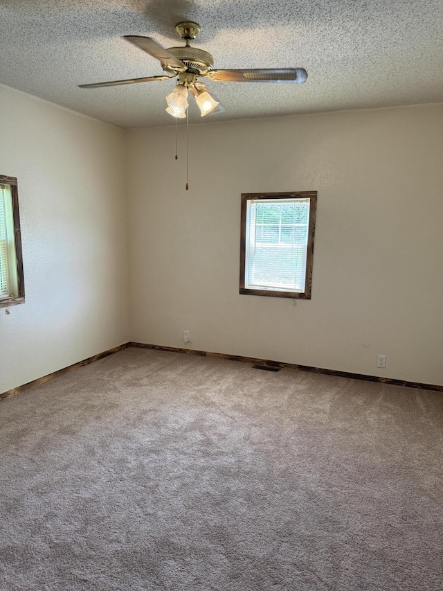 carpeted spare room featuring baseboards, a ceiling fan, and a textured ceiling