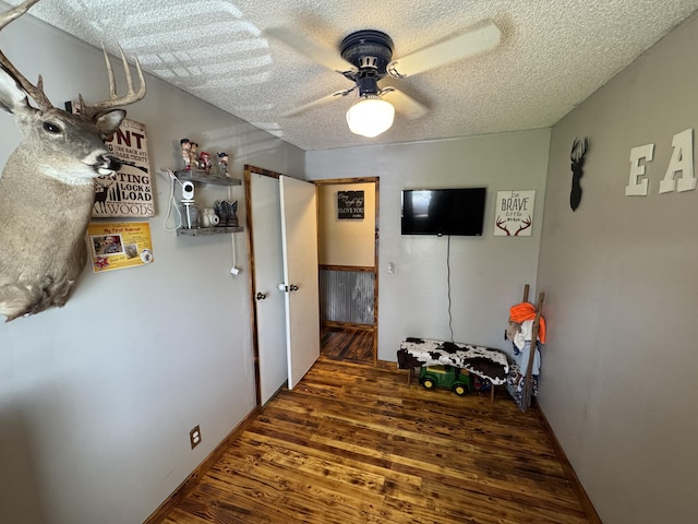 bedroom with a textured ceiling, ceiling fan, and wood finished floors