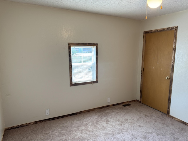 carpeted spare room featuring visible vents, a textured ceiling, and baseboards