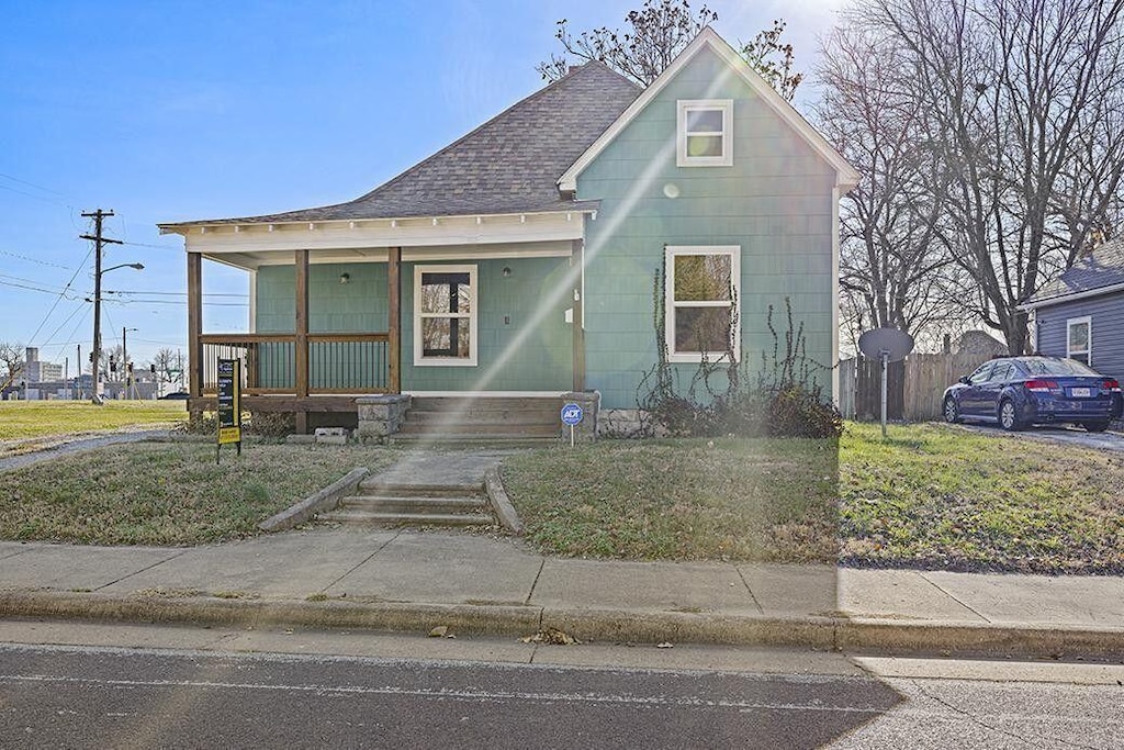 722 W Brower St, Springfield, MO 65802 - view of front facade with covered porch, a front yard, and roof with shingles