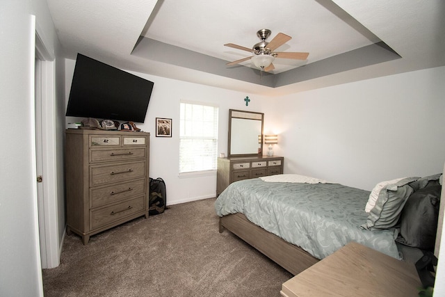 carpeted bedroom with baseboards, a raised ceiling, and ceiling fan