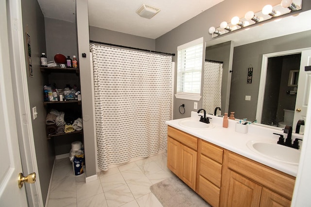 bathroom featuring a sink, double vanity, marble finish floor, and visible vents
