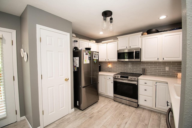 kitchen with white cabinetry, backsplash, light wood-style floors, and stainless steel appliances