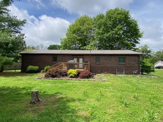 rear view of house featuring a yard, a deck, brick siding, and french doors