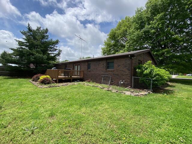 back of property with a lawn, a wooden deck, and brick siding
