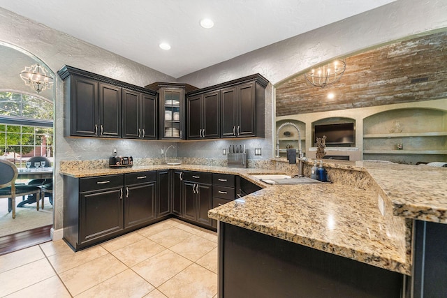 190 Windy Ridge Dr, Hollister, MO 65672 - kitchen with light stone counters, an inviting chandelier, glass insert cabinets, and a textured wall
