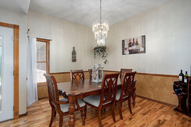dining room with an inviting chandelier, light wood-style floors, and wainscoting