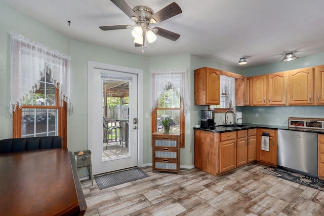 kitchen with dishwasher, ceiling fan, a sink, brown cabinets, and dark countertops