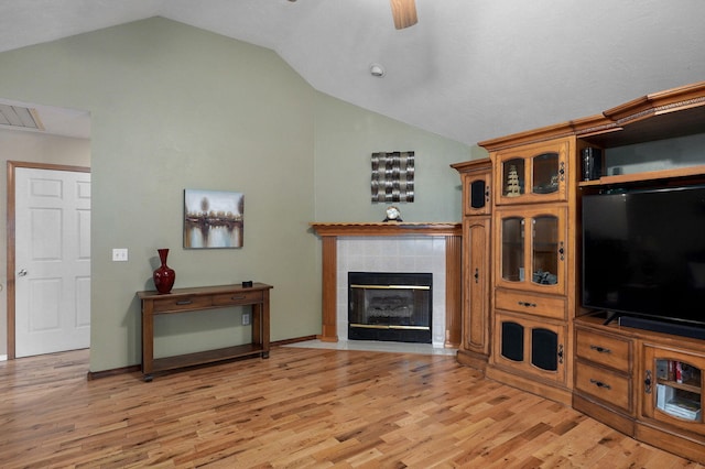 living area with lofted ceiling, a fireplace, light wood-style flooring, and ceiling fan