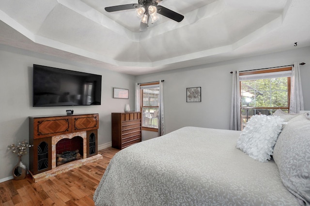 bedroom with a raised ceiling, baseboards, a ceiling fan, and wood finished floors