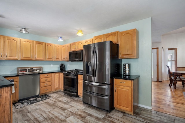 kitchen featuring appliances with stainless steel finishes, a toaster, light brown cabinets, and light wood-style floors