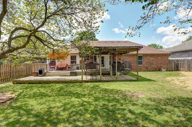 back of property with a fenced backyard, a wooden deck, and a lawn