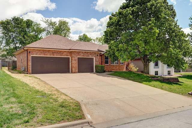 ranch-style home featuring fence, brick siding, driveway, a garage, and a front lawn