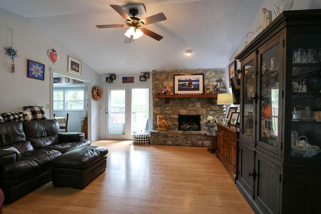 living room featuring vaulted ceiling, a fireplace, a ceiling fan, and light wood-style floors