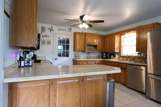 kitchen featuring a peninsula, stainless steel appliances, light countertops, and a ceiling fan