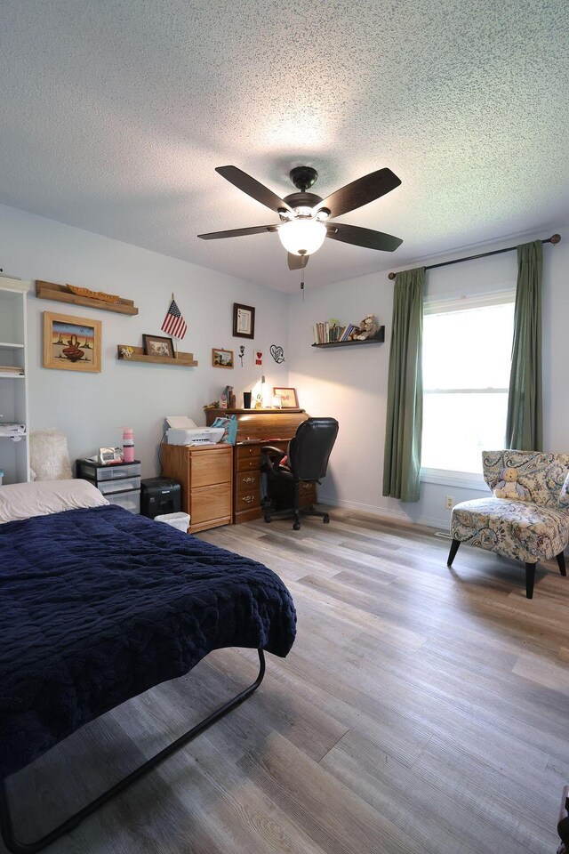 bedroom with light wood finished floors, a textured ceiling, and ceiling fan