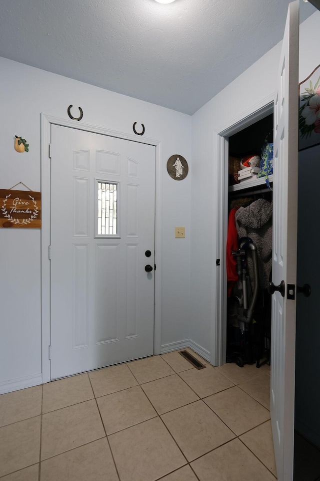 entryway with light tile patterned floors, baseboards, and visible vents