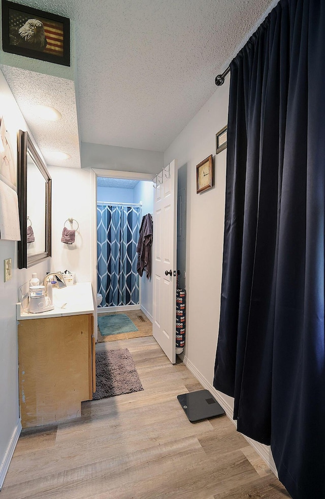 bathroom with baseboards, vanity, a textured ceiling, and wood finished floors