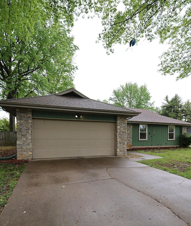 single story home featuring board and batten siding, driveway, a garage, stone siding, and roof with shingles