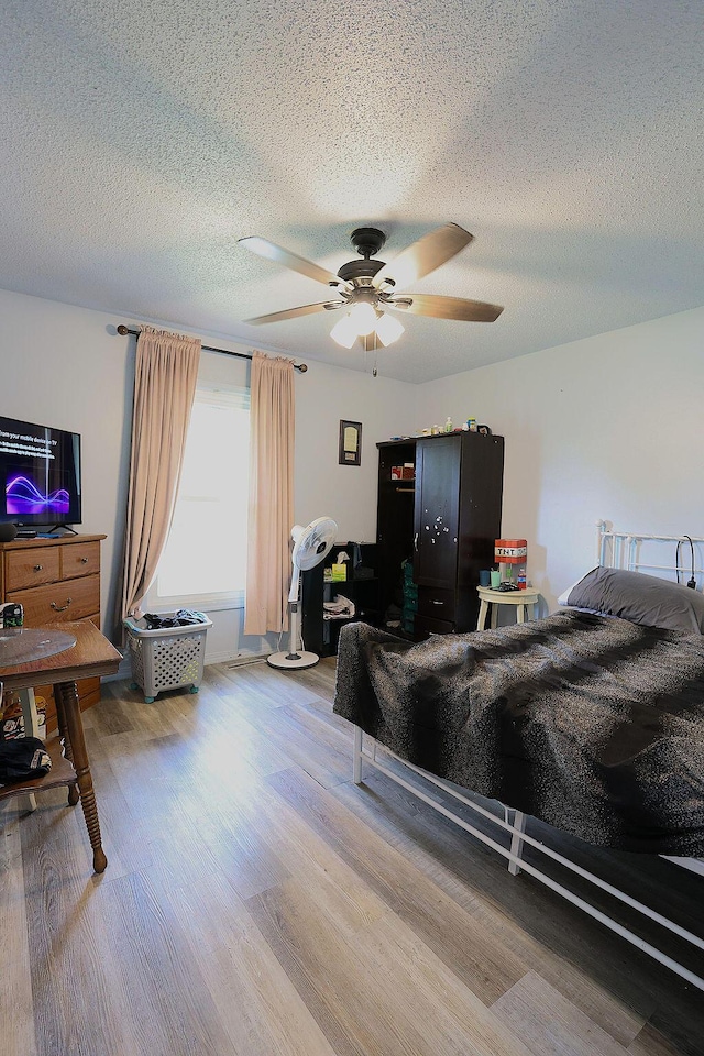 bedroom with ceiling fan, a textured ceiling, and light wood-type flooring