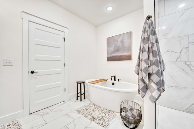 bathroom featuring baseboards, marble finish floor, a soaking tub, and recessed lighting