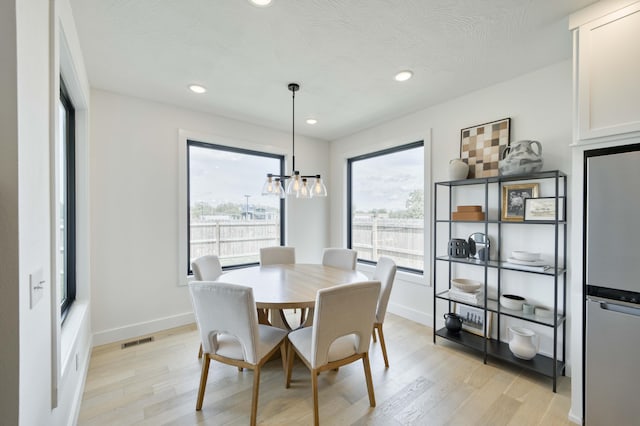 dining room with light wood finished floors, baseboards, and visible vents