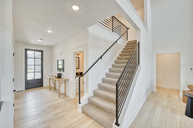 foyer featuring recessed lighting, light wood-type flooring, baseboards, and stairs