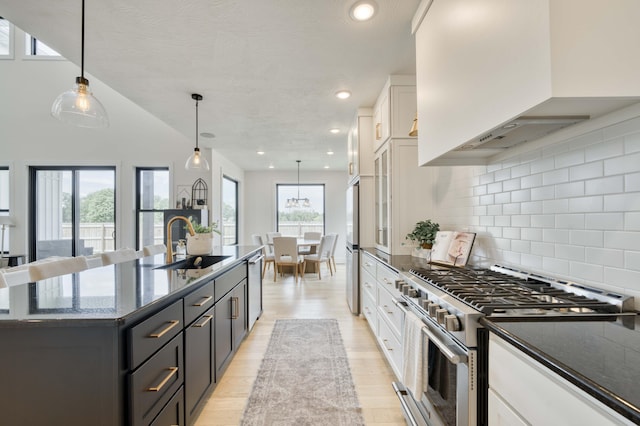 kitchen with a sink, white cabinets, custom range hood, tasteful backsplash, and appliances with stainless steel finishes