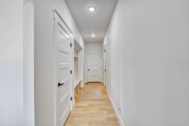 corridor with light wood finished floors, baseboards, and recessed lighting