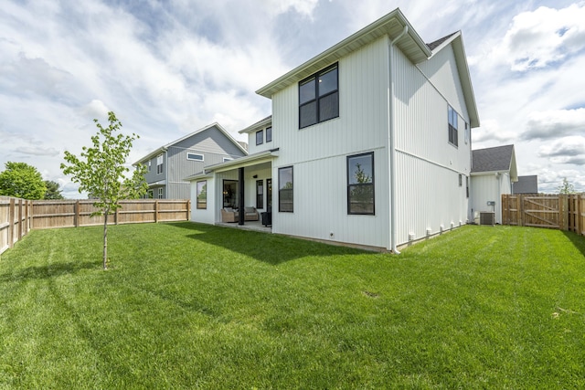 rear view of property with central air condition unit, a lawn, and a fenced backyard